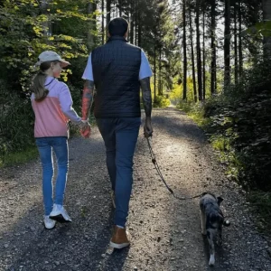 Vater, Tochter und Hund beim Waldspaziergang
