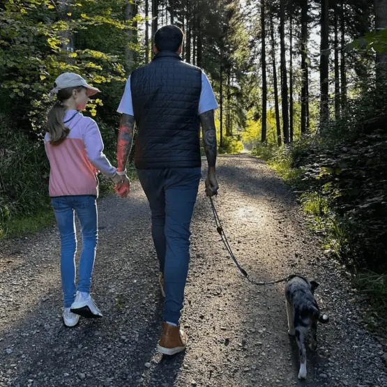 Vater, Tochter und Hund beim Waldspaziergang