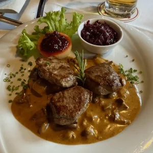 Ein angerichteter Teller mit Fleisch, Sauce und Garnitur.