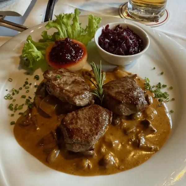 Ein angerichteter Teller mit Fleisch, Sauce und Garnitur.