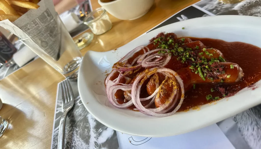 Rehbratwurst mit Curry-Saucen, roten Zwiebeln und Pommes im Gasthaus Adler Lahr