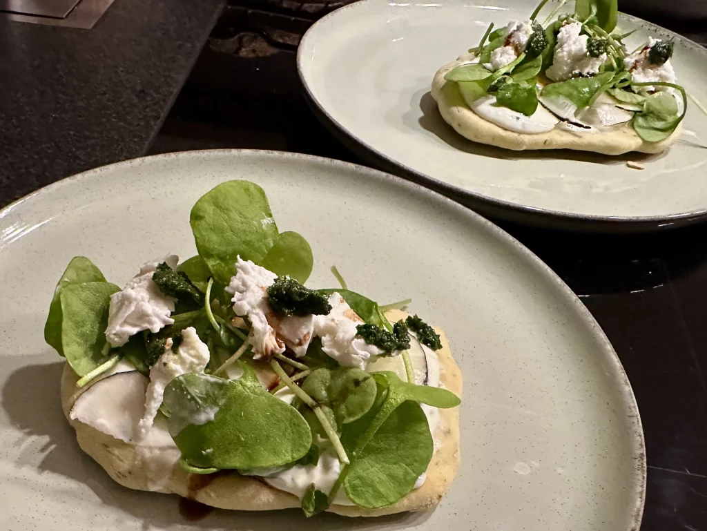 Bärlauch Fladenbrot aus dem Schwarzwald frisch serviert mit Salat und cremigem Belag auf Teller angerichtet