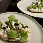 Bärlauch Fladenbrot aus dem Schwarzwald frisch serviert mit Salat und cremigem Belag auf Teller angerichtet