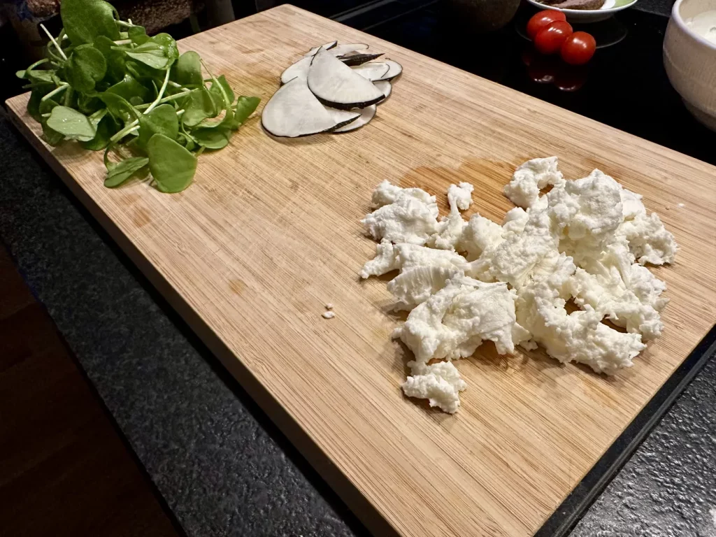 Ziegenkäse wird für den Belag des Bärlauch Fladenbrots vorbereitet und zerkleinert