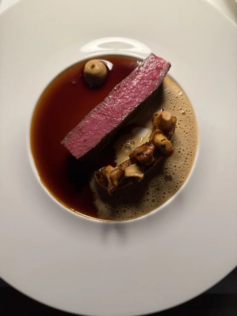 Rosa gegarte Rinderhüfte mit Pfifferlingen, Artischocke und dunkler Sauce.